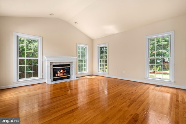 unfurnished living room featuring light wood-type flooring, a high end fireplace, visible vents, and lofted ceiling