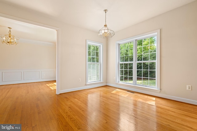 unfurnished dining area featuring light wood-style floors, visible vents, a notable chandelier, and baseboards