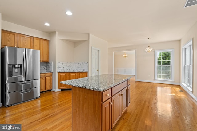 kitchen with brown cabinetry, stainless steel fridge, and visible vents