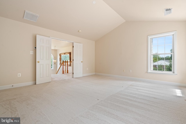 unfurnished room featuring visible vents, vaulted ceiling, light carpet, and baseboards