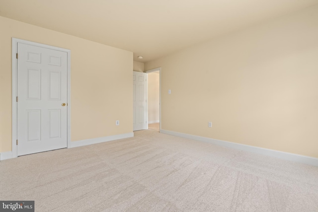 unfurnished bedroom with light colored carpet and baseboards