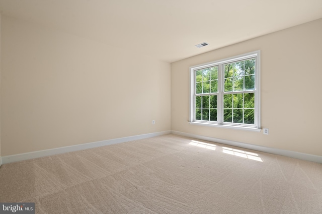 unfurnished room with visible vents, baseboards, and light colored carpet