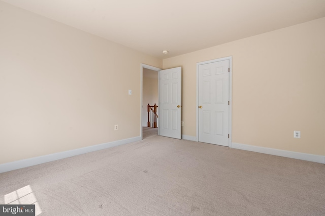 spare room with light carpet and baseboards