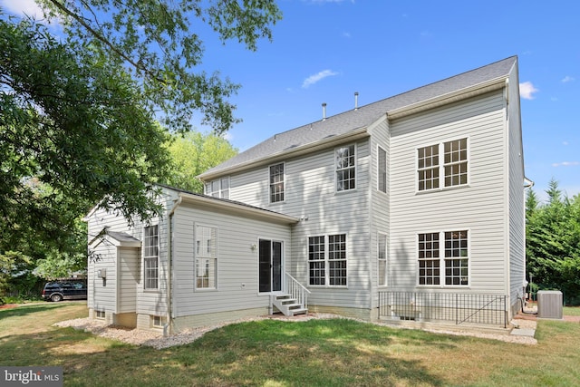 rear view of property with entry steps, central air condition unit, and a yard