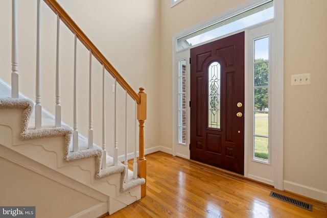 foyer with baseboards, a wealth of natural light, visible vents, and light wood-style floors