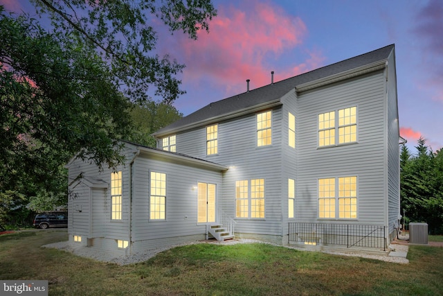 rear view of property with entry steps, a yard, and cooling unit