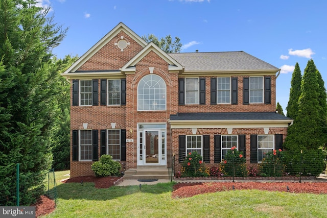 view of front of home featuring a shingled roof, brick siding, and a front lawn