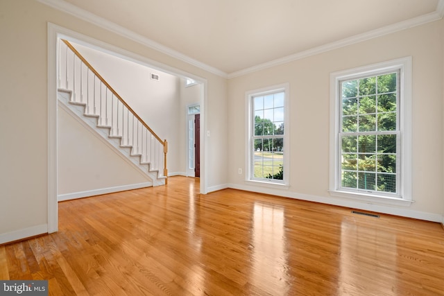 interior space with light wood-style flooring, visible vents, baseboards, ornamental molding, and stairway