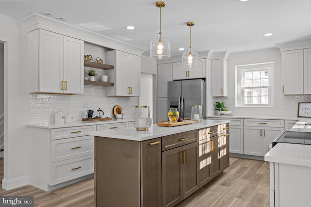 kitchen featuring pendant lighting, white cabinetry, stainless steel fridge, a center island, and light wood-type flooring