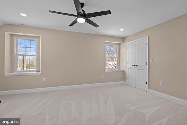 carpeted spare room featuring plenty of natural light, ceiling fan, and vaulted ceiling