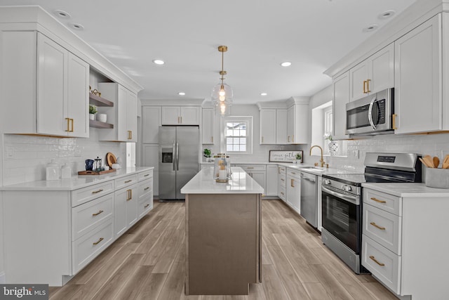 kitchen with light hardwood / wood-style flooring, a kitchen island, pendant lighting, stainless steel appliances, and white cabinets