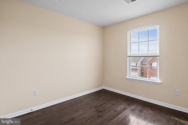 unfurnished room with dark wood-style floors, visible vents, and baseboards