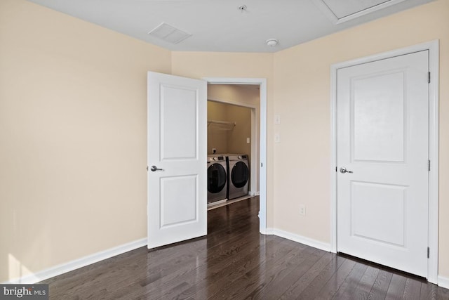 unfurnished bedroom with visible vents, washing machine and dryer, dark wood finished floors, and baseboards