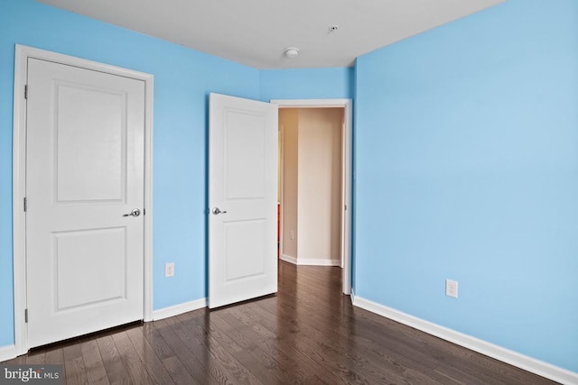 unfurnished bedroom featuring dark wood-style floors and baseboards