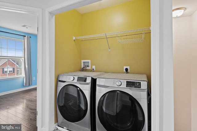 clothes washing area featuring wood finished floors, laundry area, baseboards, and separate washer and dryer