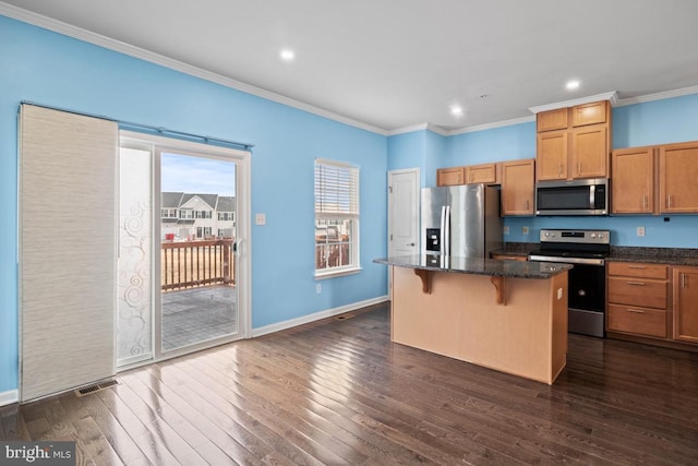 kitchen with dark wood-type flooring, a breakfast bar, a kitchen island, visible vents, and appliances with stainless steel finishes