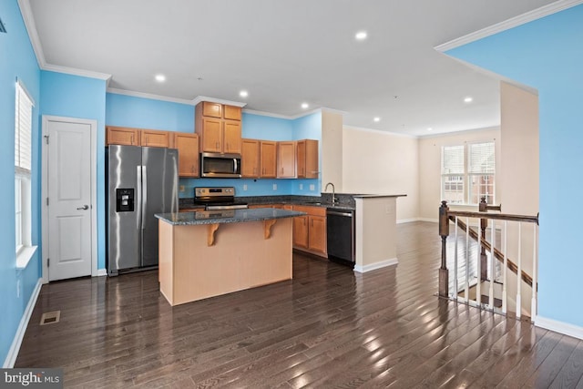 kitchen featuring a center island, dark wood-style flooring, stainless steel appliances, a sink, and baseboards