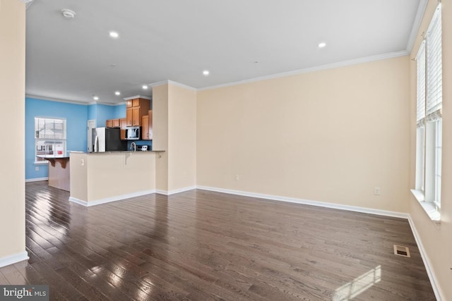 unfurnished living room with ornamental molding, dark wood-style flooring, visible vents, and baseboards