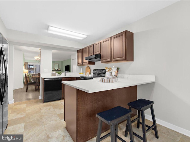 kitchen with a notable chandelier, kitchen peninsula, a breakfast bar area, and black appliances