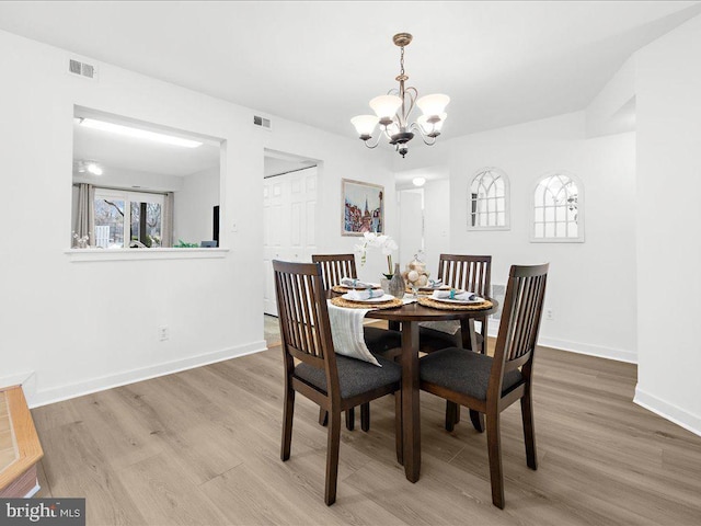 dining space with hardwood / wood-style floors and a notable chandelier