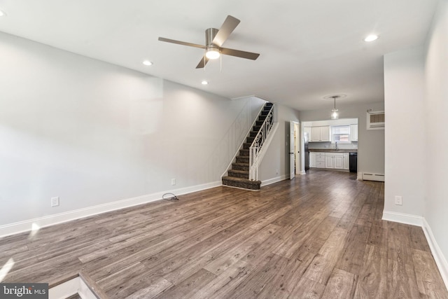 unfurnished living room with ceiling fan, a baseboard heating unit, sink, and dark hardwood / wood-style flooring