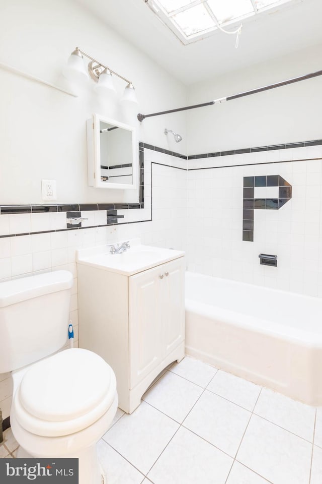 full bathroom featuring tile patterned floors, vanity, tiled shower / bath combo, tile walls, and toilet