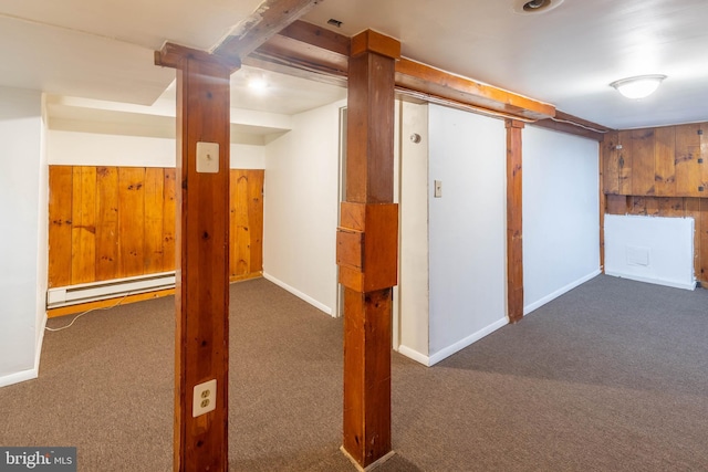 basement featuring dark carpet, baseboard heating, and wood walls