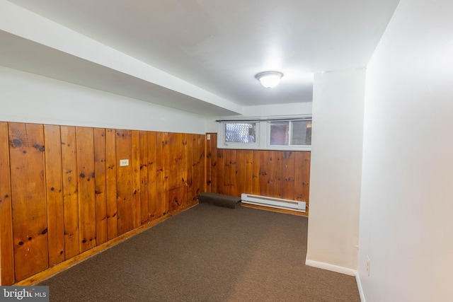 interior space with wooden walls, dark carpet, and a baseboard heating unit