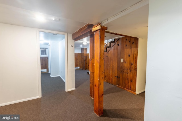 corridor with wooden walls, dark colored carpet, and a baseboard heating unit