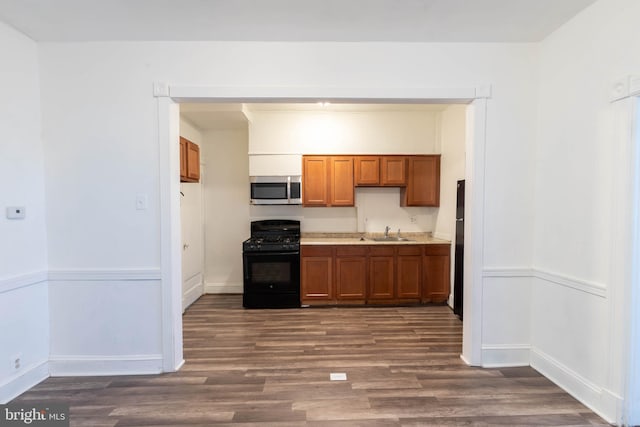 kitchen featuring black gas range, dark hardwood / wood-style flooring, and sink