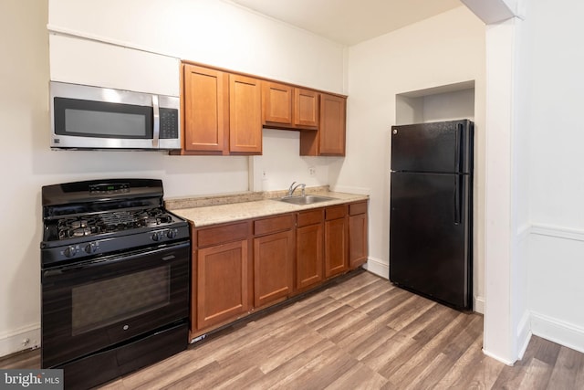 kitchen featuring black appliances, light wood-type flooring, and sink