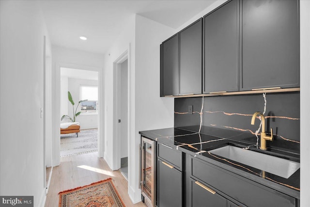 kitchen with decorative backsplash, beverage cooler, sink, gray cabinets, and light hardwood / wood-style floors