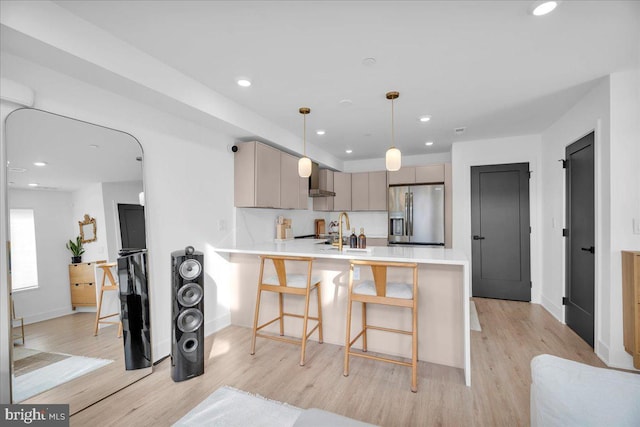 kitchen with gray cabinetry, pendant lighting, sink, stainless steel refrigerator with ice dispenser, and kitchen peninsula