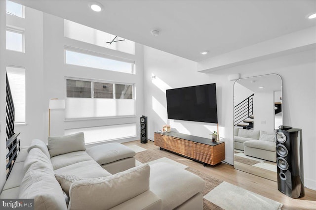 living room with a healthy amount of sunlight, a towering ceiling, and light hardwood / wood-style floors