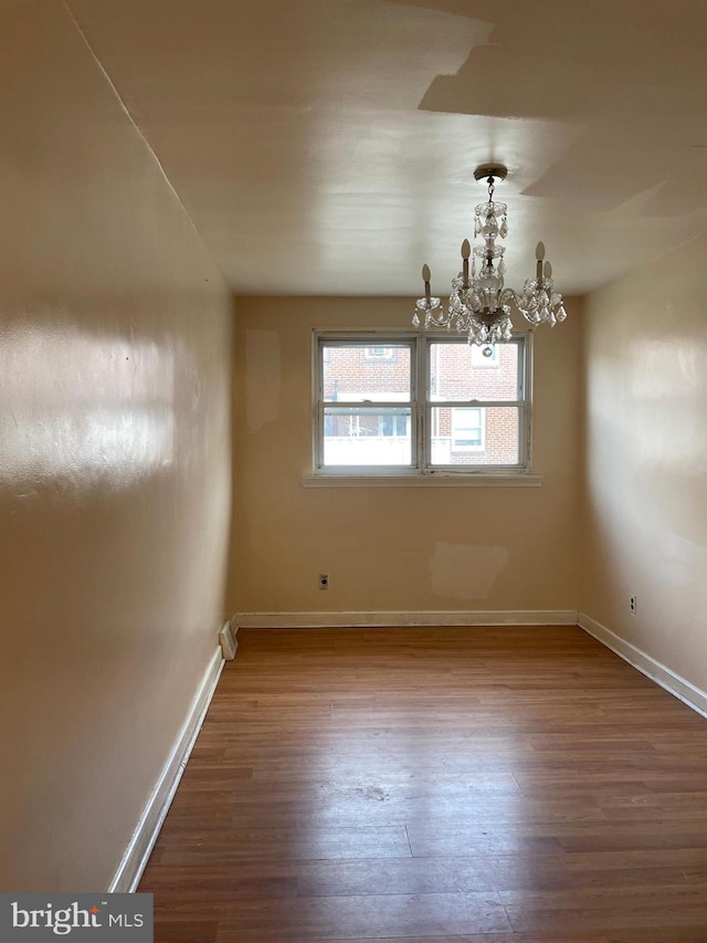 unfurnished dining area with hardwood / wood-style flooring and a chandelier