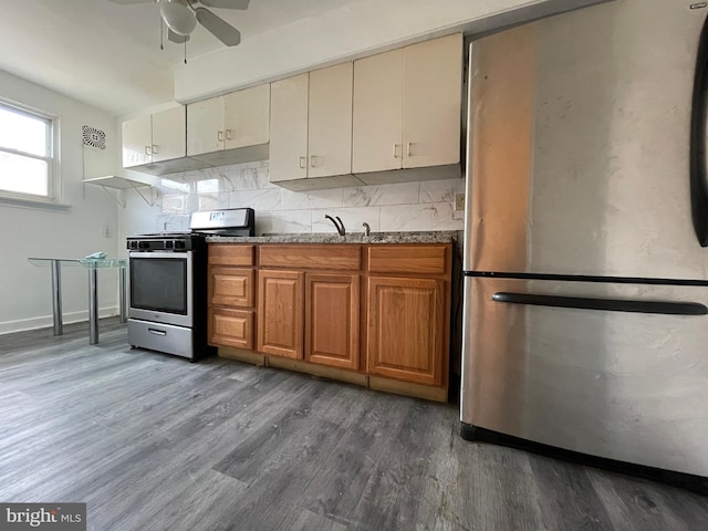 kitchen with dark hardwood / wood-style floors, ceiling fan, backsplash, and appliances with stainless steel finishes