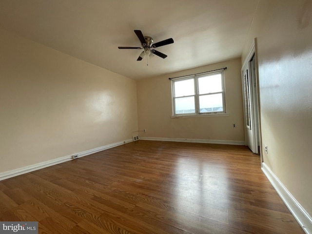 empty room with ceiling fan and dark wood-type flooring