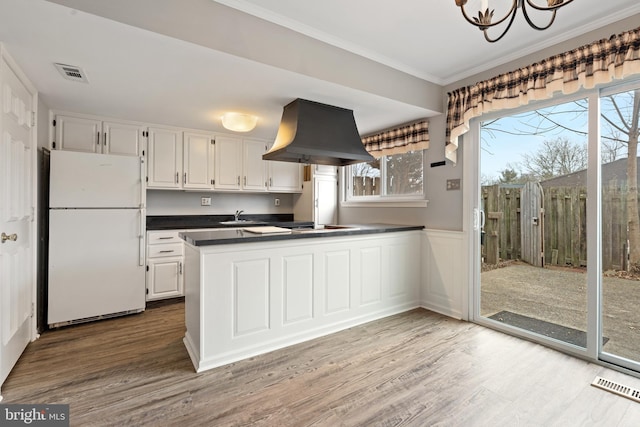 kitchen featuring white cabinetry, sink, white fridge, island range hood, and light wood-type flooring