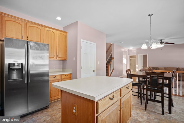 kitchen featuring stainless steel fridge with ice dispenser, a center island, decorative light fixtures, and ceiling fan with notable chandelier