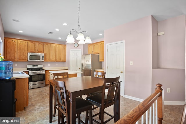 kitchen featuring a kitchen island, appliances with stainless steel finishes, a notable chandelier, and hanging light fixtures