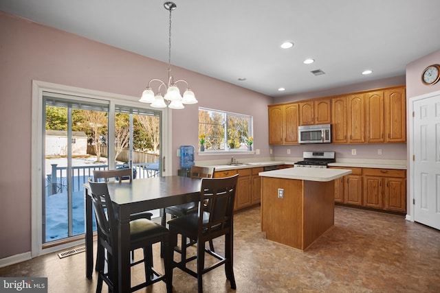 kitchen with sink, a center island, hanging light fixtures, a notable chandelier, and appliances with stainless steel finishes