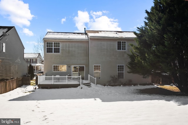 snow covered rear of property with a deck