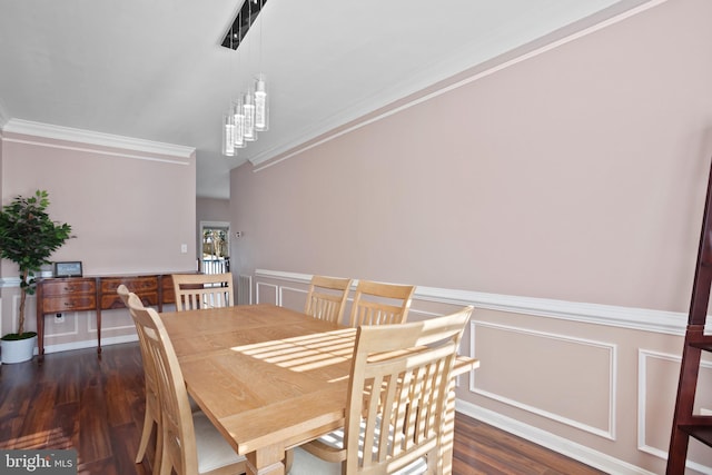 dining space with dark wood-type flooring, crown molding, and a chandelier