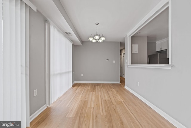 unfurnished dining area with light hardwood / wood-style floors and a notable chandelier