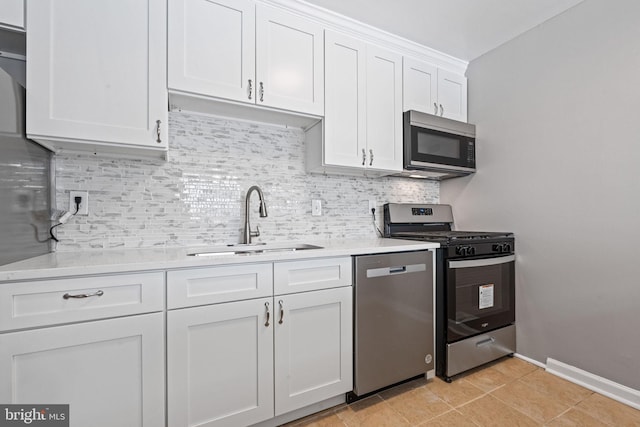 kitchen featuring appliances with stainless steel finishes, backsplash, sink, light tile patterned floors, and white cabinetry