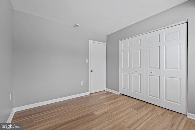 unfurnished bedroom featuring light wood-type flooring and a closet