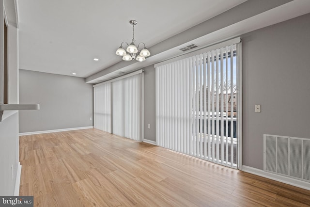 unfurnished dining area featuring a chandelier and light hardwood / wood-style floors