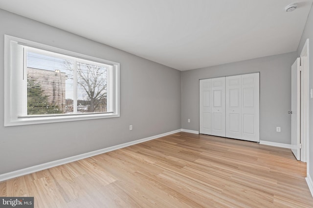 unfurnished bedroom featuring multiple windows, a closet, and light wood-type flooring