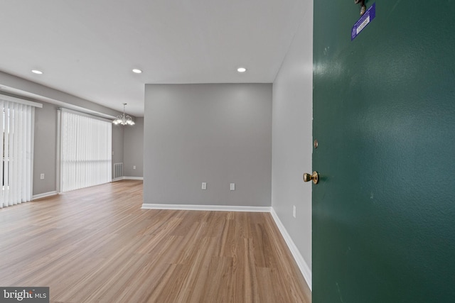 unfurnished room with a chandelier and light hardwood / wood-style floors