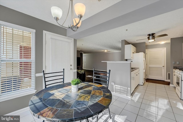 dining space with ceiling fan with notable chandelier, a textured ceiling, and light tile patterned floors